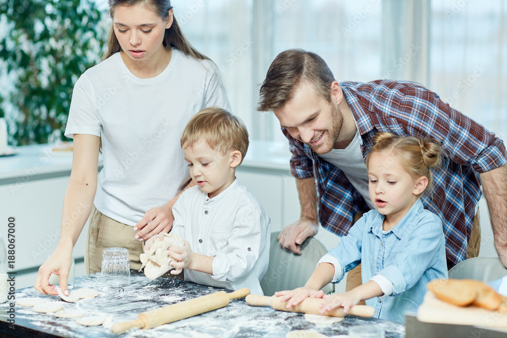 Obraz premium Two cute siblings helping their parents make homemade pastry in the kitchen