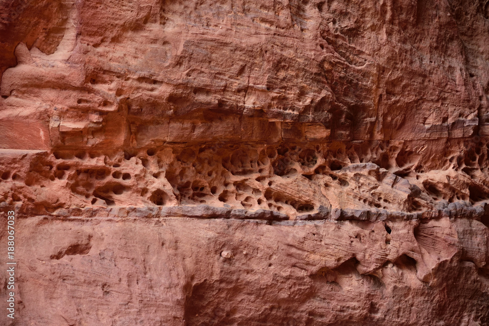 Winderosionslöcher in Sedimentband einer roten Sandsteinwand