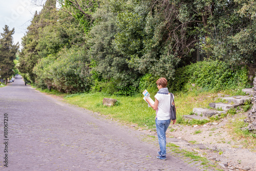 Tourist with map getting around ancient ruins in Rome old town, Appia Antica way, heritage of early italian history, travel destination for tourists. Toned image. © fabio lamanna