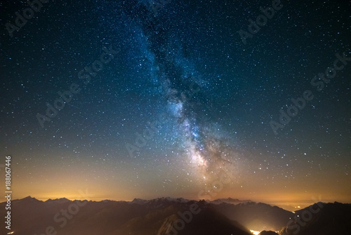 Milky Way and starry sky captured at high altitude in summertime on the Alps with glowing Aosta Valley below, travel destination in Italy.