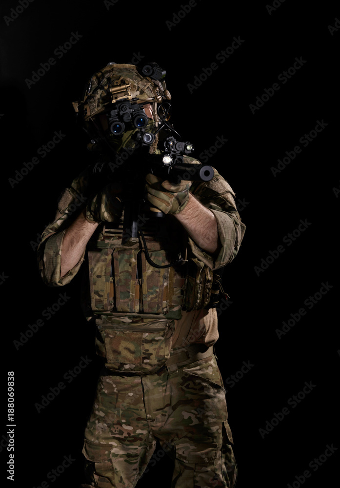 Army soldier in Combat Uniform with assault rifle, combat helmet and night vision device. Studio shot, dark background Army soldier in Combat Uniform with assault rifle, combat helmet and night vision device. Studio shot, dark background