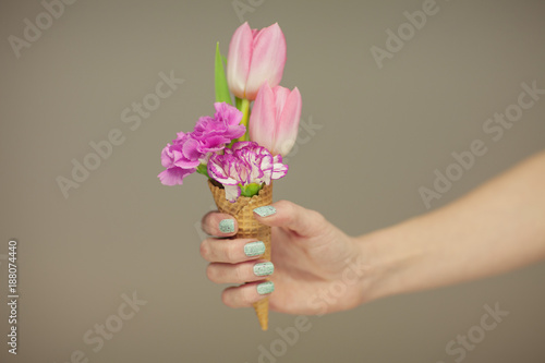 woman hands holding spring flowers in an ice cream cone, sensual studio shot can be used as background