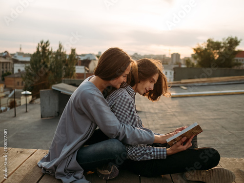 Couple sits on a roof top reading a book. Literature self-improvement, leisure, hobby, bookworms concept