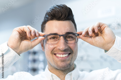 Foto Man trying on glasses in optical store while smiling happy