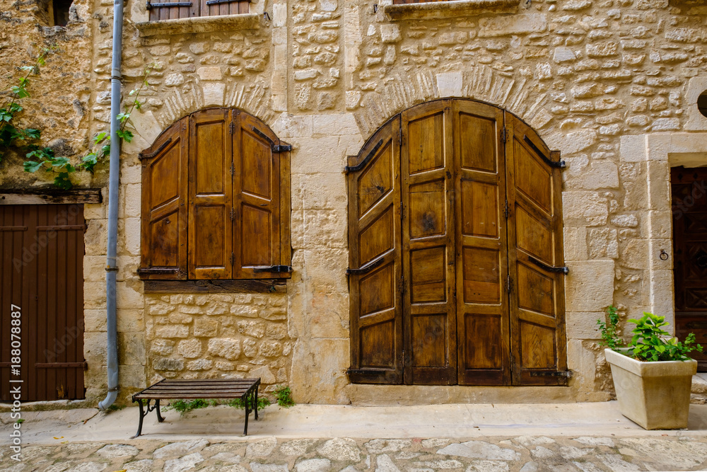 Façade d'ancienne maison avec la porte et les volets en bois. Village de Simiane-la-Rotonde, Provence, France.