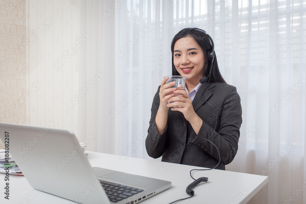 Call center operator. Drinking water while working with laptop computer Call center operator. Drinking water while working with laptop computer