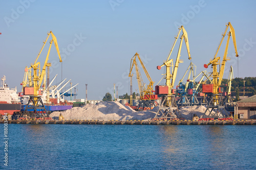 Port cargo wharf crane over blue sky background. Bulk cargo ship under port crane bridge, Odessa, Ukraine.