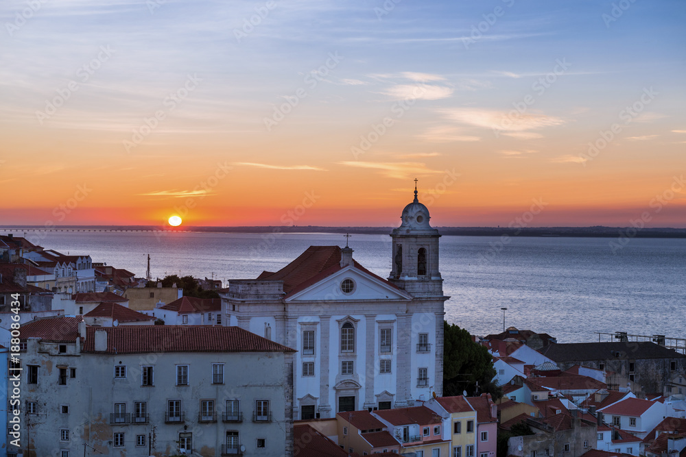View of a Church in the Alfama neighborhood from the Portas do Sol viewpoint at sunrise in Lisbon, Portugal; Concept for travel in Portugal, visit Portugal and most beutiful places in Portugal