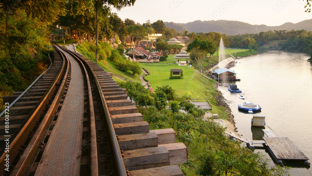 nature landscape railroad tracks and fountain on river with green grass meadow in the resort or hotel for tourist travel on relax holiday with warm sunlight at kanchanaburi in Thailand