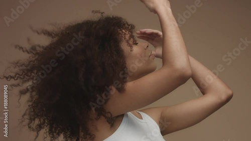 closeup portrait of mixed race black woman shaked head and her curly hair flying in air slowly. Touching it