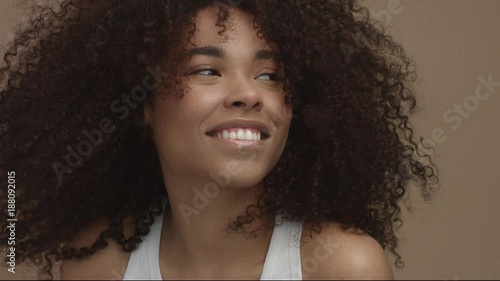 happy laughing black woman with wind moving her cyrly hair in sytdio