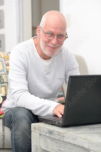 Senior man with laptop sitting in sofa