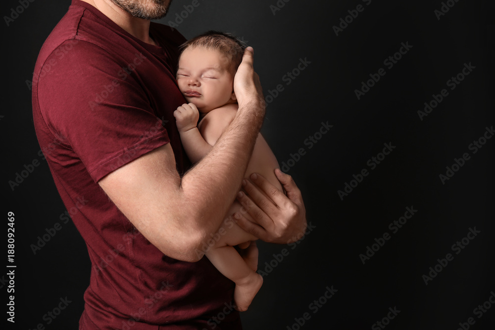 Father with cute little baby on dark background Father with cute little baby on dark background