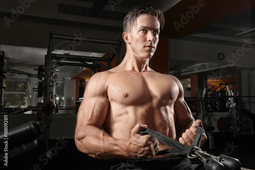 Young man training on exercise machine in gym