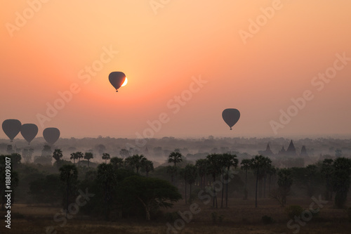 Silhouette of ancient temples and pagodas and several hot-air balloons above the ancient plain of Bagan in Myanmar (Burma) at sunrise. Copy space.