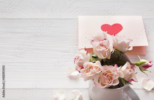 Pink rose flowers bouquet and handmade greeting card on white rustic wood © Prostock-studio