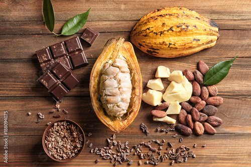 Composition with cocoa pod and products on wooden background, top view