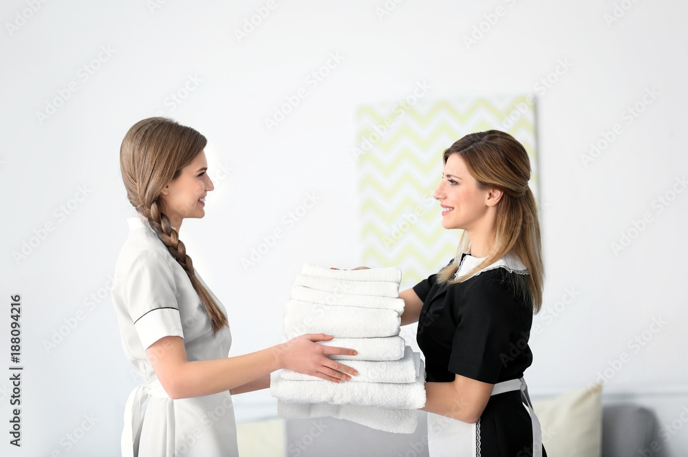 Chambermaid in uniform teaching trainee indoors Chambermaid in uniform teaching trainee indoors