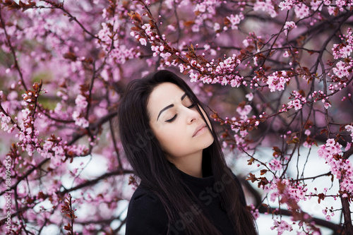 Winter, spring portrait of young beautiful brunette woman with long hair wearing warm coat.