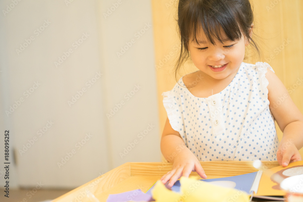 Cute little girl cutting shapes out of colored paper. Children being creative, developing imagination, creativity, do it yourself concept Cute little girl cutting shapes out of colored paper. Children being creative, developing imagination, creativity, do it yourself concept