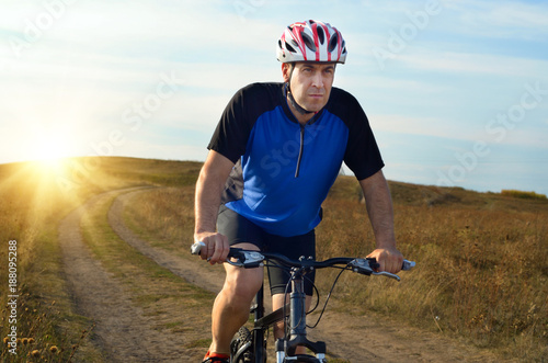 Male cyclist driving by rural dirt road outdoors
