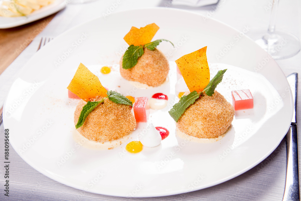 Plum dumplings with cinnamon, white chocolate and vanilla sauce served in a restaurant