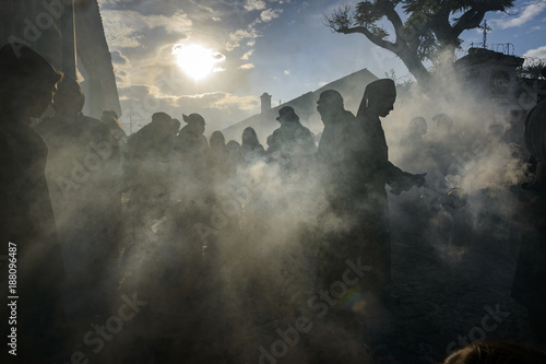 Antigua, Guatemala - April 19, 2014: Silhouette of men wearing black robes and hoods spreading incense in a street of the city of Antigua during a procession of the Holy Week in Antigua, Guatemala