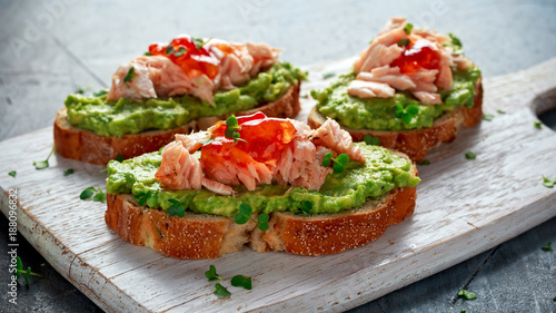 Homemade Toast sandwich with Salmon, Avocado and chilli jam on wihte wooden board. healthy food