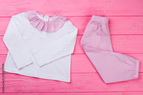 Pajama set for toddler girls. White top with cute ruffles and fine pink pattern pants. Nice sleepwear for little ones. © DenisProduction.com