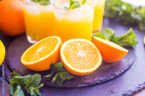 glass jar of fresh orange juice with fresh fruits on dark table.