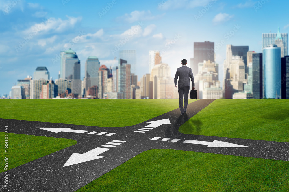 Young businessman at crossroads in uncertainty concept Young businessman at crossroads in uncertainty concept