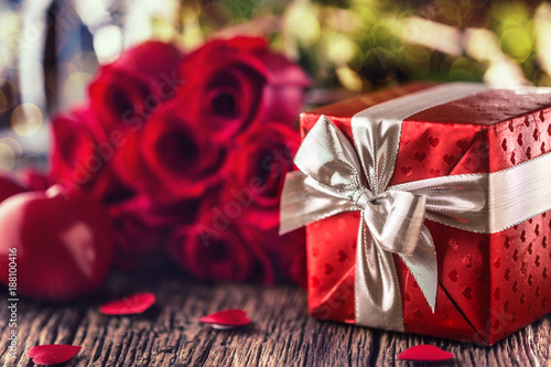 Valentine wedding concept. Bouquet of roses and wrapped gift with red hearts ...