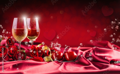Valentines or wedding concept. Wine cups red roses and romantic setting for t...