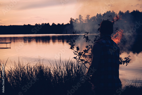 Silhouette of man lakside campfire photo