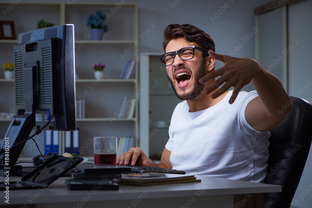 Young man staying late in office to do overtime work Young man staying late in office to do overtime work