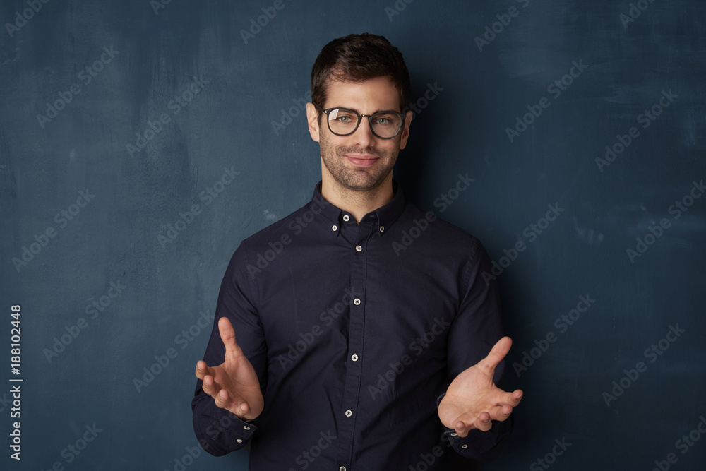 What should i do? Young man studio portrait. Close-up shot of a young businessman standing at dark background and looking at camera. 