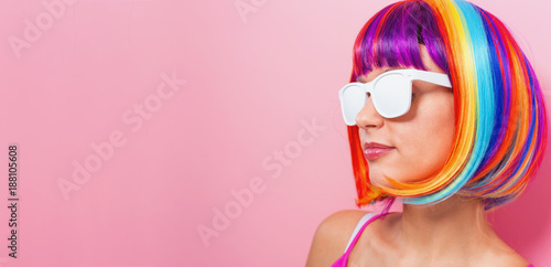 Beautiful woman in a colorful wig on a pink background