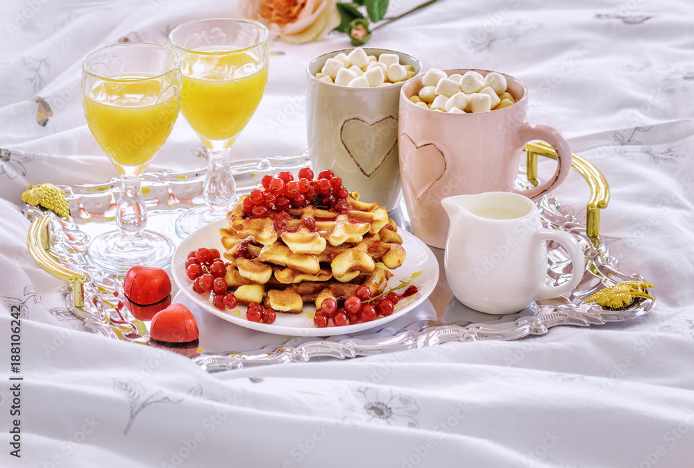 Romantic breakfast with Belgian waffles, honey, red currant, cappuccino with marshmallow and fresh orange juice Romantic breakfast with Belgian waffles, honey, red currant, cappuccino with marshmallow and fresh orange juice