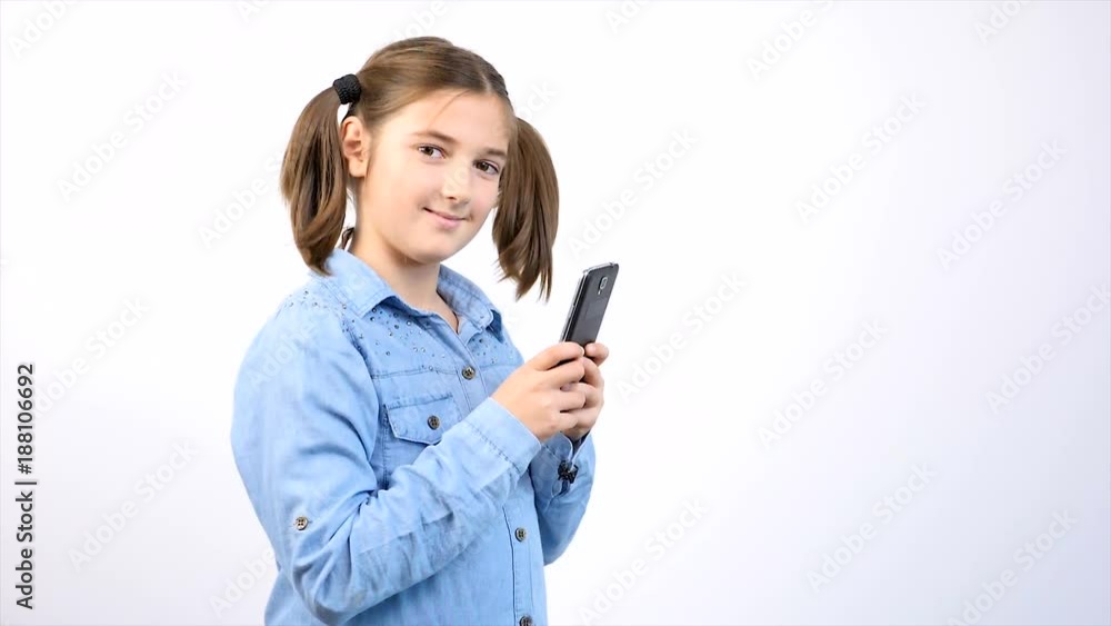 Toung pretty girl child using smartphone on gray background in studio Toung pretty girl child using smartphone on gray background in studio