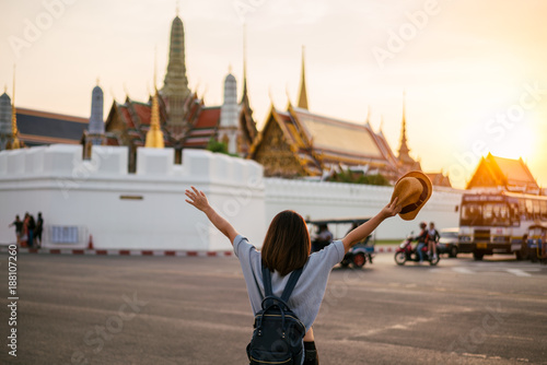 Young woman traveler travelling into Grand palace and Wat Phra Kaew at sunset Bangkok, Thailand. Amazing beautiful landmark of Bangkok Thailand. Temple of the Emerald Buddha.