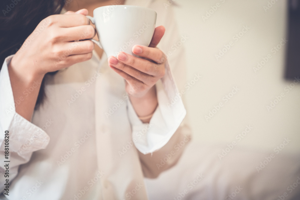 Asian girl who just wake up in the morning as relaxed. She's read one book on the bed. She opened the window to receive the light of the morning sun. She was holding a glass of coffee to drink it. Asian girl who just wake up in the morning as relaxed. She's read one book on the bed. She opened the window to receive the light of the morning sun. She was holding a glass of coffee to drink it.