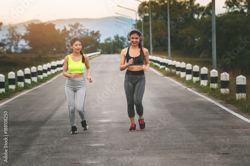 Happy and beautiful women joggers running on road. Fitness and workout wellness concept.