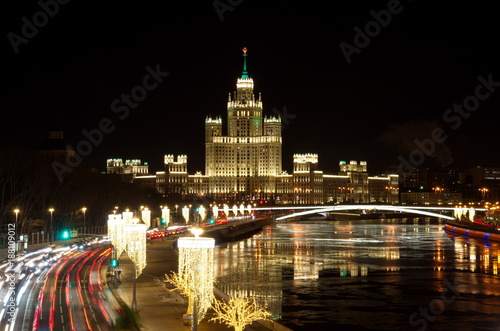 Evening view on the high-rise building of the Kotelnicheskaya embankment and Big Ustinsky bridge. Christmas illuminations on Moskvoretskaya embankment, Moscow, Russia