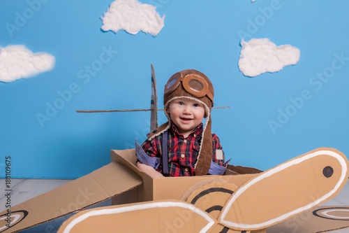 Little child girl in a pilot's costume is playing and dreaming of flying over the clouds.