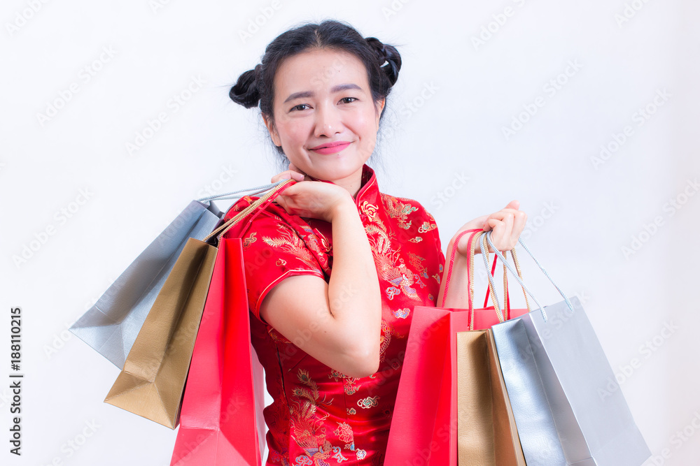 Young asian woman wearing chinese dress traditional cheongsam with Carrying a shopping bag and smile. Chinese New Year Festivities, New Year Celebration, Shopping concept, on white background. Young asian woman wearing chinese dress traditional cheongsam with Carrying a shopping bag and smile. Chinese New Year Festivities, New Year Celebration, Shopping concept, on white background.