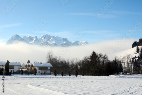 Winter landscape at early morning in Austria with snow, wooden buildings, blue sky and copy space.