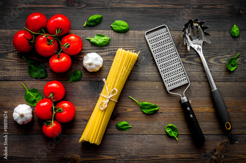 Main ingredients for italian pasta. Spaghetti, tomatoes, garlic, green basil on dark wooden background top view