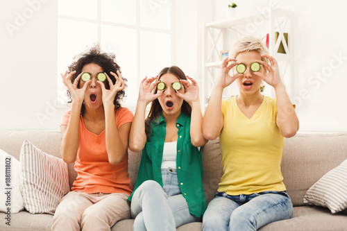 Three beautiful girls covering eyes with cucumber pieces photo