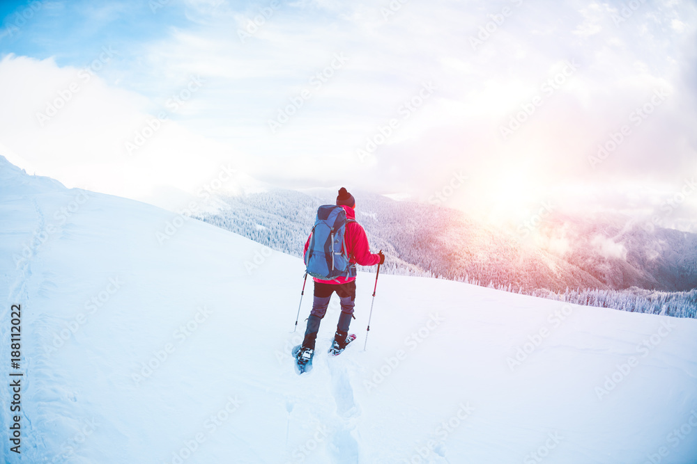 A man in snowshoes in the mountains. A man in snowshoes in the mountains.