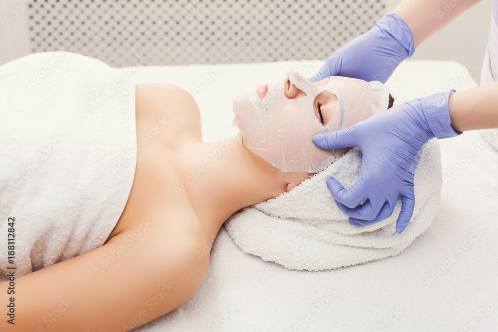 Obraz premium Woman gets face mask by beautician at spa